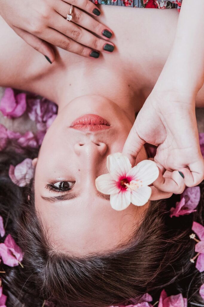 pexels-photo-2144413-2144413 Elegant photoshoot featuring a woman holding a pink flower amidst petals.